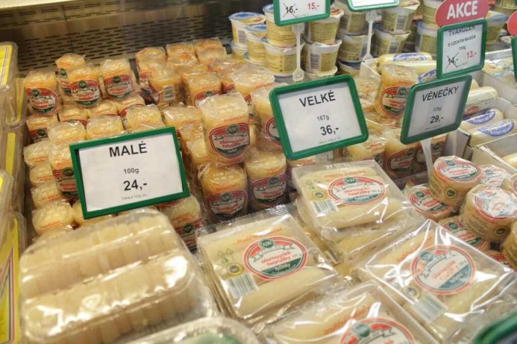 Regál plný rôznych typov tvarohového syra v obaloch.