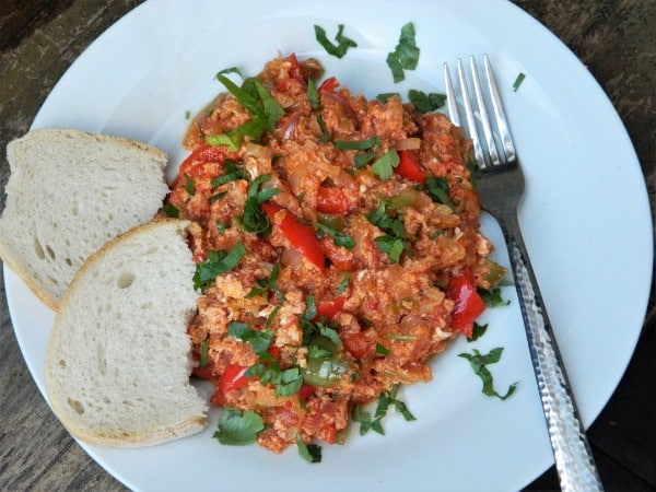 Zmes varených vajíčok, paprík a paradajok servírovaná s pečivom