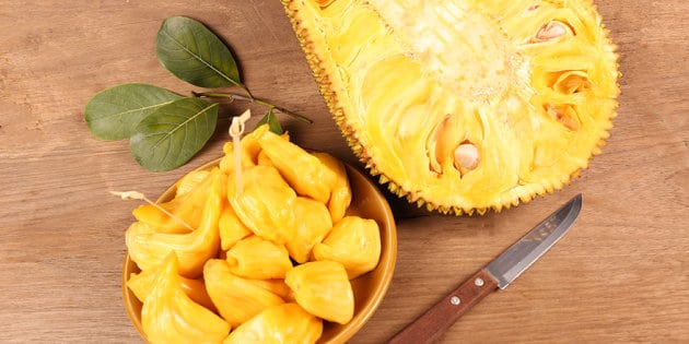 Rozkrojený jackfruit a mištička s nakrájaným jackfruitom s vedľa položeným nožom.