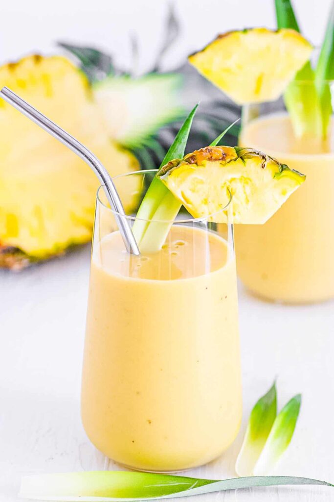 Ovocné smoothie v pohári so slamkou ozdobené plátkom ananásu.