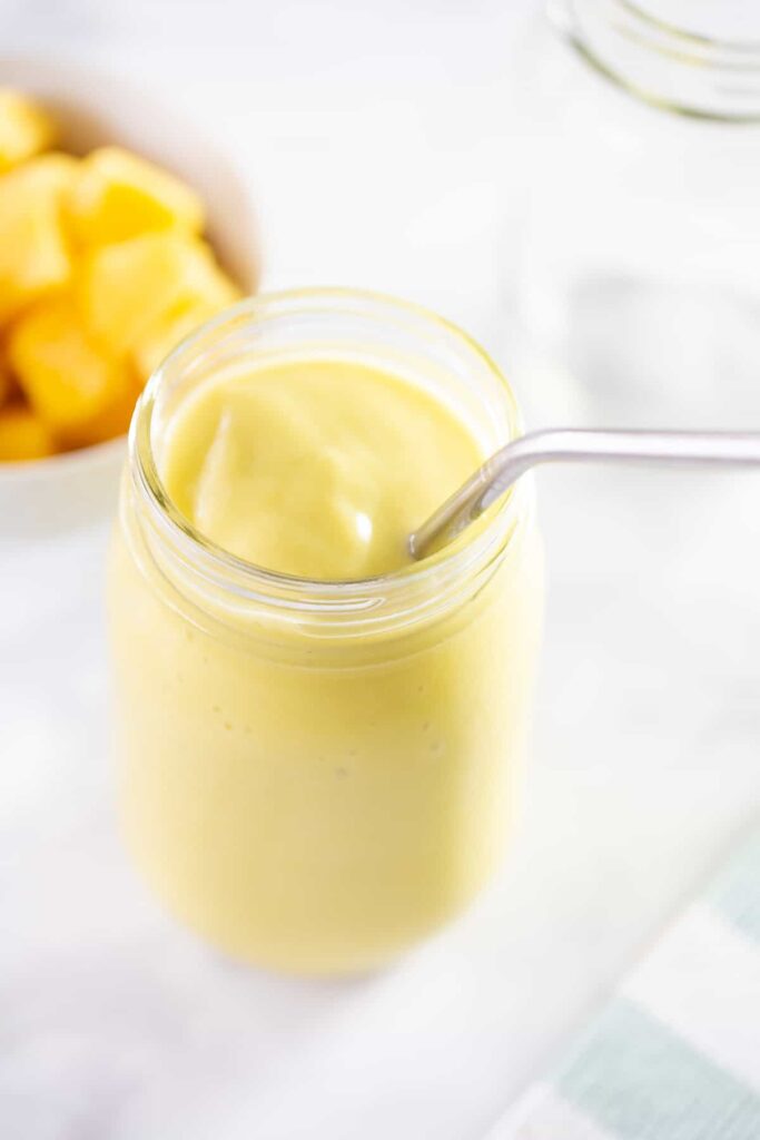 Mangové smoothie s avokádom v pohári so slamkou.