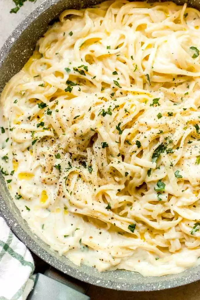 Omáčka z cesnaku so špagetami servírovaná v hlbokom tanieri a posypaná čerstvými bylinkami.
