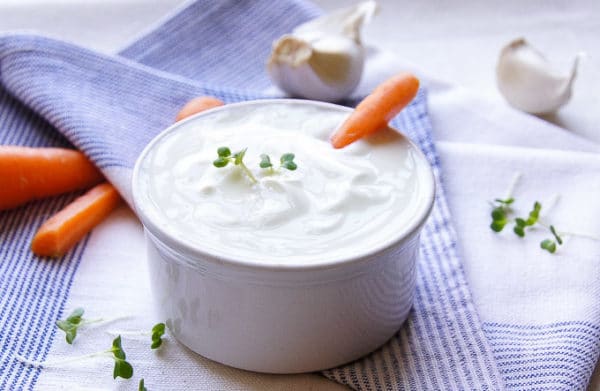 Jogurtovo-majonézová omáčka s cesnakom servírovaná v miske s čerstvou mrkvou.