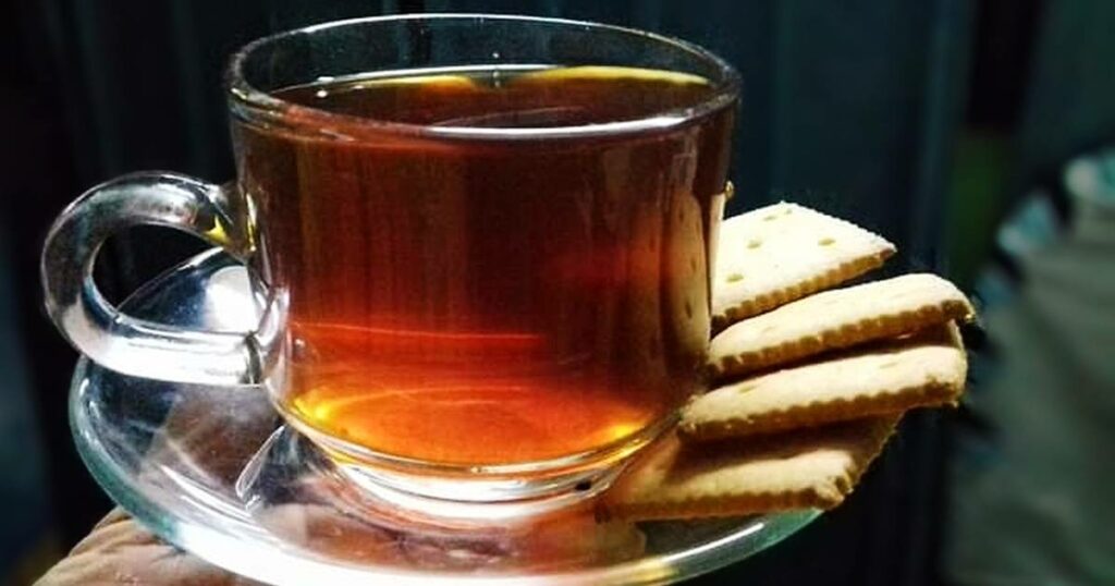 Čaj z cibule v sklenenom hrnčeku na podtácku so sušienkami.