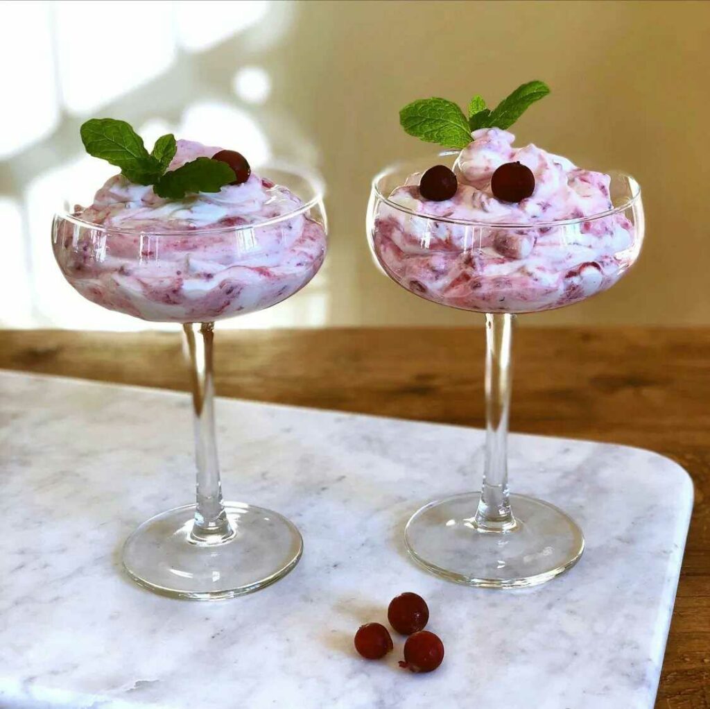 Dva poháre plnené krémom a ovocím, ozdobené čerstvou mätou.