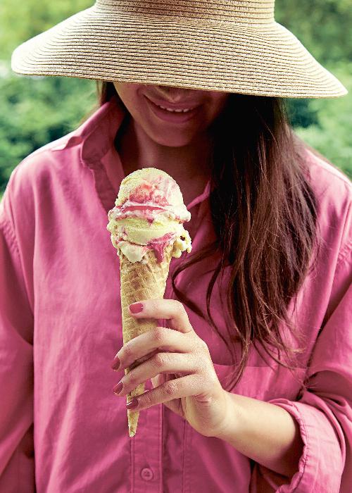 Žena s klobúkom, ktorá drží v ruke vanilkovo-ovocnú zmrzlinu.