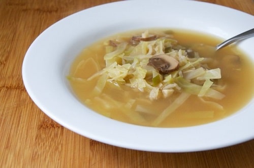 Kapustová polievka s hubami, servírovaná v bielom tanieri.