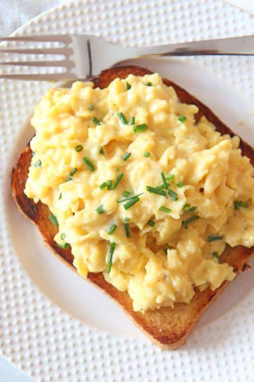 Vaječina s kyslou smotanou servírovaná na plátku chleba a ozdobená nasekanou pažítkou.