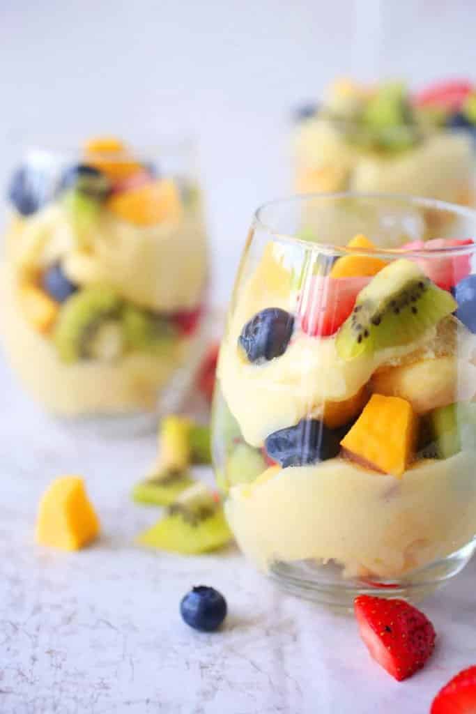 Dezert z vanilkového pudingu, čerstvého ovocia a cukrárskych piškótov servírovaný v pohároch.