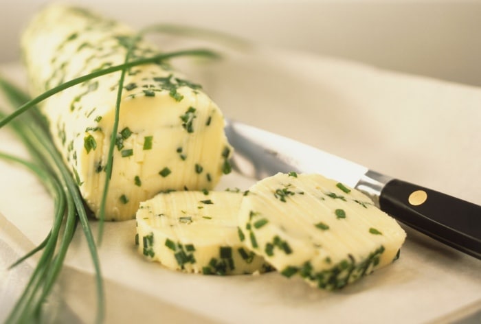 Pažítkové maslo na doske s nožom.