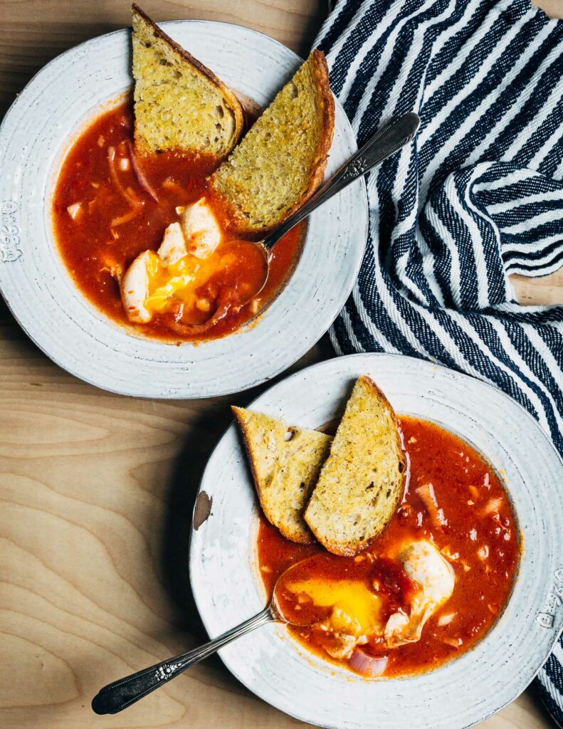 Tomatová polievka s vajcom a chlebom v bielom tanieri.
