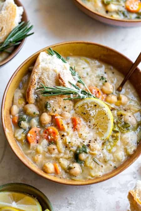 Fazuľová polievka so zeleninou v hlbokom tanieri, ozdobená plátkom citróna a bylinkami.