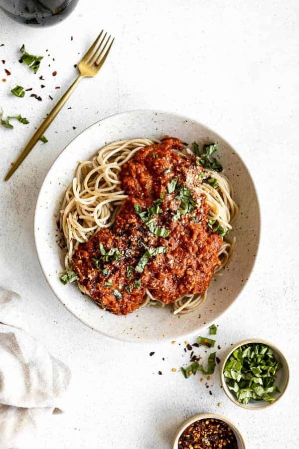 Špagety s paradajkovou omáčkou na tanieri s vedľa položenou vidličkou.